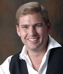 A man with blonde hair and wearing a vest.