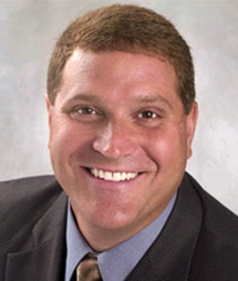 A man in a suit and tie smiling for the camera.